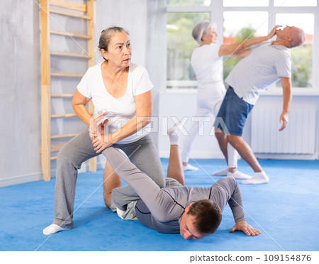 Old woman twisting her opponent's arm during self-defense classes Old woman twisting her opponent's arm during self-defense classes 109154876