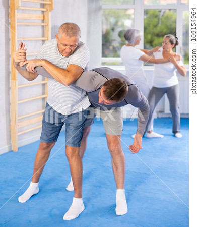 Old man twisting her opponent's arm during self-defense classes Old man twisting her opponent's arm during self-defense classes 109154964
