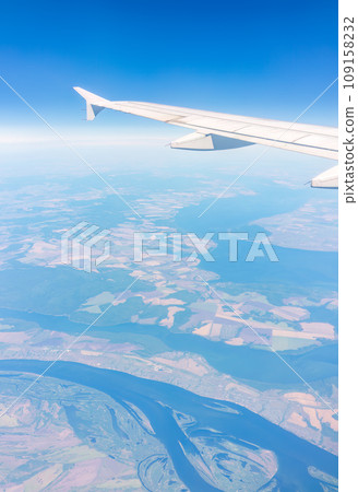 Aerial view from airplane window above green ground. View from the airplane window with beautiful clouds at sunrise 109158232