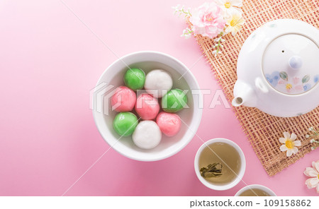 Tang Yuan(sweet dumplings balls), a traditional cuisine for Mid-autumn, Dongzhi (winter solstice ) and Chinese new year with plum flower and tea on pastel background. 109158862
