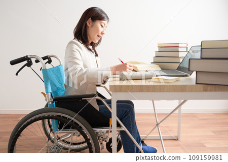 Woman in wheelchair studying at desk 109159981