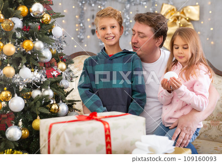 Happy father with son and daughter near the Christmas tree in living room. Merry Christmas 109160093