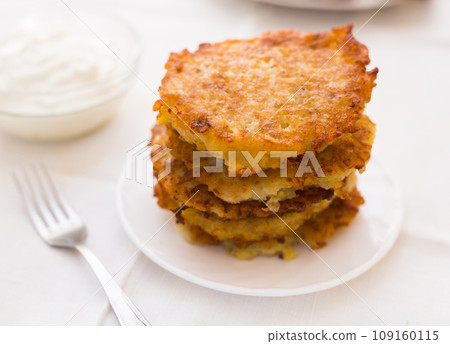Potato pancakes with sour cream on white plate 109160115
