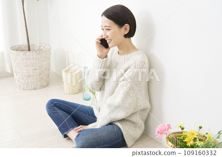 A woman calling on her smartphone in the living room A woman calling on her smartphone in the living room 109160332