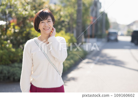 A smiling woman in her 50s walking in a residential area 109160602