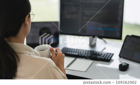 Developer programmer drinking coffee and checking code on monitor for programming to developing web 109162002
