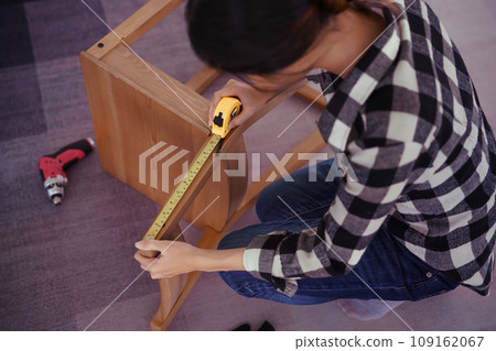 Women measuring length of chair with measure tape while assembling and renovation chair furniture Women measuring length of chair with measure tape while assembling and renovation chair furniture 109162067