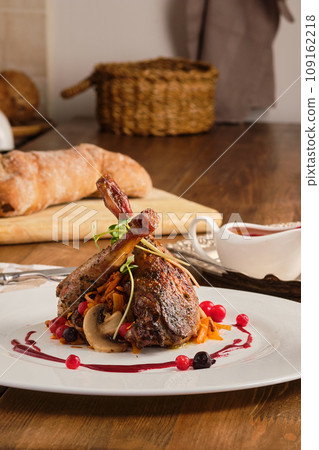 Plate with baked partridge thigh with cranberry sauce 109162218