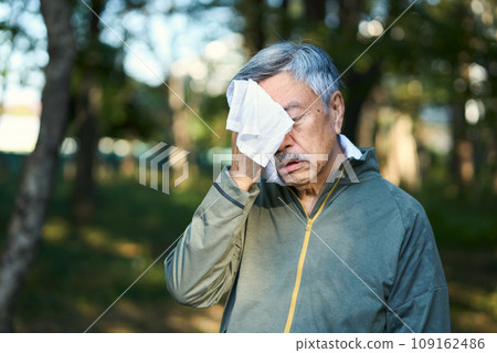 Senior man wiping sweat after exercising 109162486