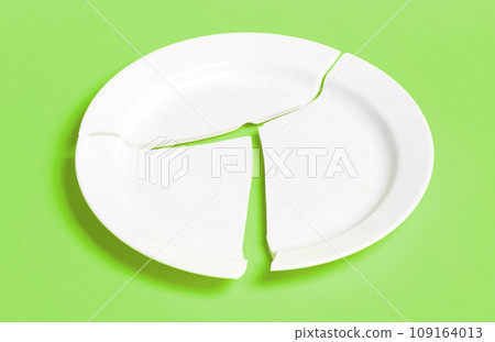 Broken white plate on a solid background Broken white plate on a solid background 109164013