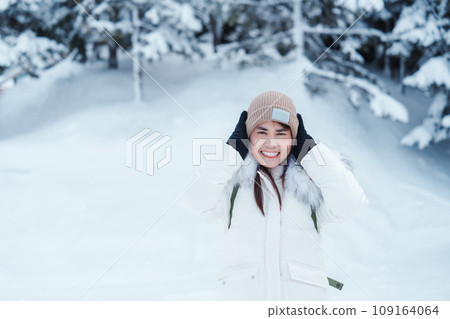 happy Traveler with Sweater and backpack walking on snow covered forest in frosty weather. Winter Travel, Adventure, Exploring and Vacation concept 109164064