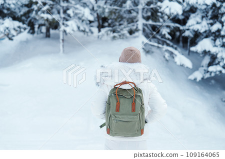Traveler with Sweater and backpack walking on snow covered forest in frosty weather. Winter Travel, Adventure, Exploring and Vacation concept Traveler with Sweater and backpack walking on snow covered forest in frosty weather. Winter Travel, Adventure, Exploring and Vacation concept 109164065