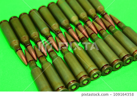 Even rows of live ammunition lined with bullets to bullets on a green surface Even rows of live ammunition lined with bullets to bullets on a green surface 109164358