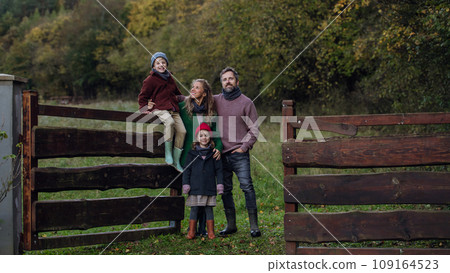 Portrait of family outdoors taking care of home garden. Mother, father and kids spending time outdoors during cold autumn day. 109164523