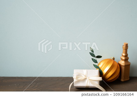 Christmas decoration ornament golden ball, gift box on wooden table. blue wall background Christmas decoration ornament golden ball, gift box on wooden table. blue wall background 109166164