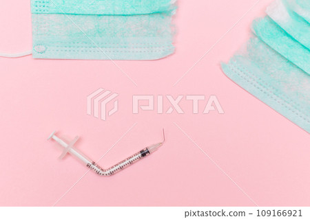 Broken Medical Syringe and Torn Medical Face Mask on the Pink Background Broken Medical Syringe and Torn Medical Face Mask on the Pink Background 109166921