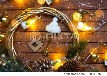 Key to house with a keychain tiny home on wooden background with Christmas decor layout. Gift for New Year, Christmas. Building, project, moving to new house, mortgage, rent and purchase real estate 109167610