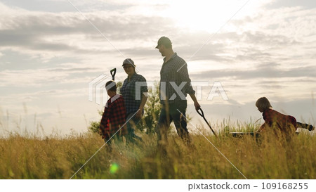 Silhouettes of farmers family with active little children walking in field after hard work day. Farmers with playful children and tools walk at farmland. Farmers family with little kids at countryside 109168255
