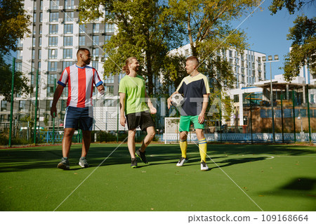 Smiling male friends football player walking among on soccer field Smiling male friends football player walking among on soccer field 109168664