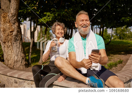 Happy overjoyed elderly man and woman couple enjoying sunny day after jogging Happy overjoyed elderly man and woman couple enjoying sunny day after jogging 109168680