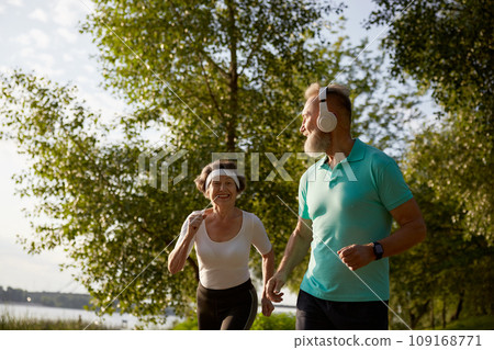 Lovely joyful retirees couple jogging outside in city park in morning Lovely joyful retirees couple jogging outside in city park in morning 109168771