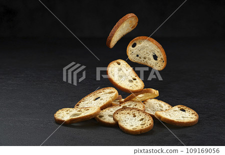 Falling bruschetta crackers, round bread croutons isolated on black background Falling bruschetta crackers, round bread croutons isolated on black background 109169056