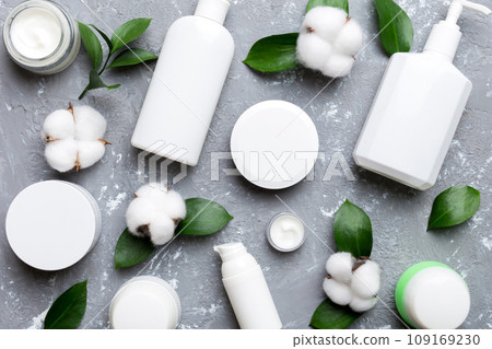 Organic cosmetic products with cotton flower and green leaves on cement background. Flat lay Organic cosmetic products with cotton flower and green leaves on cement background. Flat lay 109169230