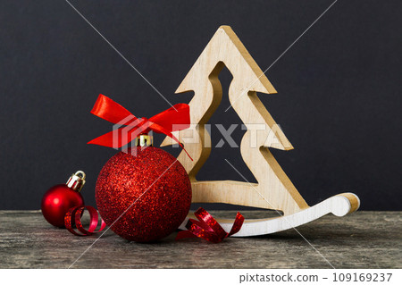 Christmas ball with decorative wooden tree on colored background. decoration bauble with ribbon bow with copy space Christmas ball with decorative wooden tree on colored background. decoration bauble with ribbon bow with copy space 109169237
