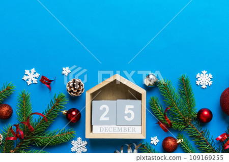 Christmas calendar 25 december. Christmas gift, fir branches, pine cones. Flat lay, top view. New Year decorations on a colored background Christmas calendar 25 december. Christmas gift, fir branches, pine cones. Flat lay, top view. New Year decorations on a colored background 109169255