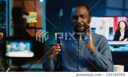 Tech content creator filming review of newly released smartphone, unboxing it and giving feedback to audience. Online star showing mobile phone recommendation to subscribers 109169369