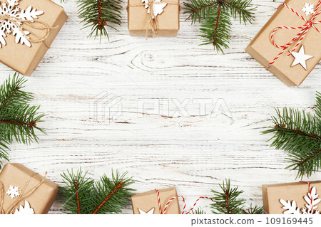 Christmas composition. Christmas gift, knitted blanket, pine cones, fir branches on wooden white background. Flat lay, top view Christmas composition. Christmas gift, knitted blanket, pine cones, fir branches on wooden white background. Flat lay, top view 109169445