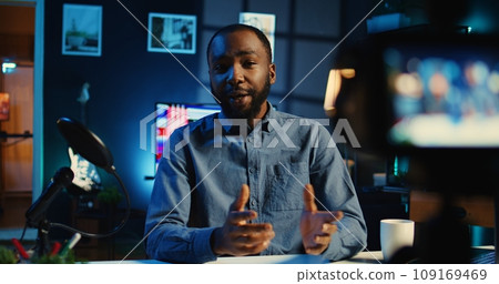 Influencer in cozy home using professional camera to film live broadcast for online streaming platforms. Internet star hosts q a session with audience members using recording tech 109169469