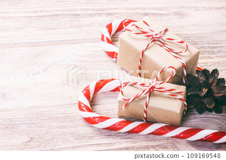 New Year's gift in a homemade box with a red bow near the and Christmas Candy canes. Toned New Year's gift in a homemade box with a red bow near the and Christmas Candy canes. Toned 109169548