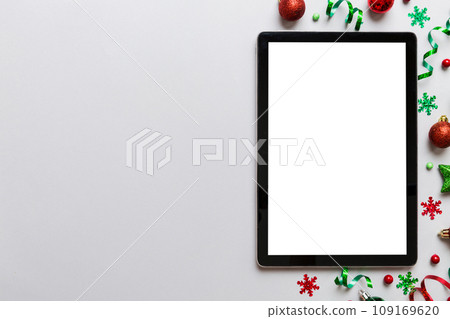 Christmas online shopping from home tablet pc with blank white display top view. Tablet with copy space on colored background with Christmas decorations balls,. Winter holidays sales background Christmas online shopping from home tablet pc with blank white display top view. Tablet with copy space on colored background with Christmas decorations balls,. Winter holidays sales background 109169620