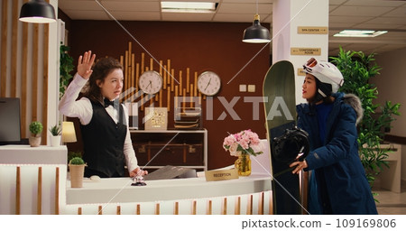 Employee gives directions to asian girl, helping her to go skiing on snowy slopes during wintertime season. Woman receptionist advising client about extreme sport at ski resort. Handheld shot. Employee gives directions to asian girl, helping her to go skiing on snowy slopes during wintertime season. Woman receptionist advising client about extreme sport at ski resort. Handheld shot. 109169806