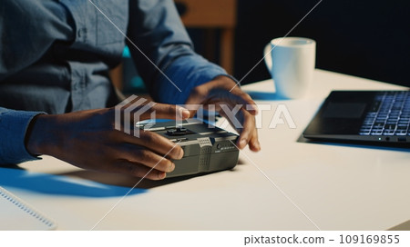 Tech content creator filming technology review of newly released V mount battery, unpacking it and presenting specifications to audience. Influencer showing charging device to subscribers 109169855