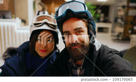 POV of couple answering videocall chat on smartphone, discussing with friends about winter adventure at alpine luxury hotel. Man and woman talking on online conference, mountain resort. Handheld shot. POV of couple answering videocall chat on smartphone, discussing with friends about winter adventure at alpine luxury hotel. Man and woman talking on online conference, mountain resort. Handheld shot. 109170065