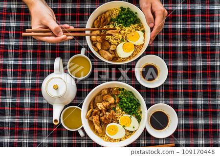 Piece of chicken in chopsticks with japanese ramen and males hands 109170448