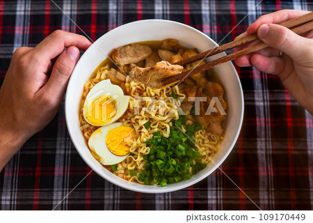 Piece of noodles in chopsticks with japanese ramen and males hands Piece of noodles in chopsticks with japanese ramen and males hands 109170449