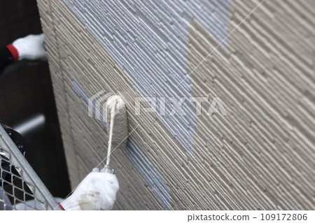 Painting girl applies intermediate coat to siding Painting girl applies intermediate coat to siding 109172806