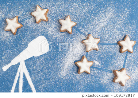 Big dipper made from cookies in form of stars and telescope made from sugar powder on blue sky 109172917