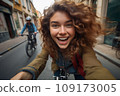 Beautiful young woman riding a bike in old town 109173005