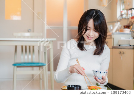 A woman living alone eating dinner in a simple house 109173403