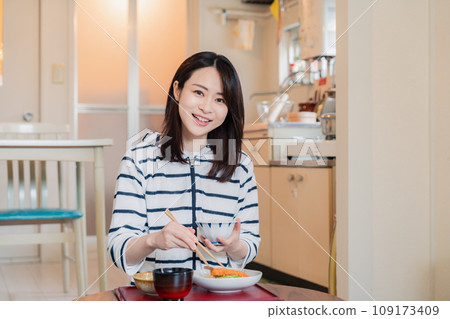 A woman living alone eating dinner in a simple house 109173409