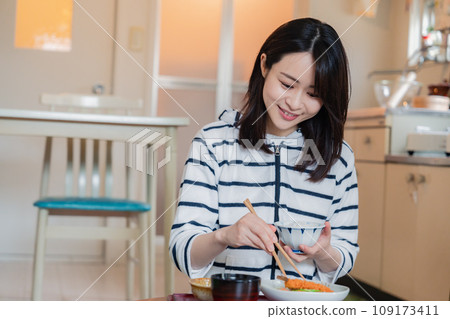 A woman living alone eating dinner in a simple house 109173411
