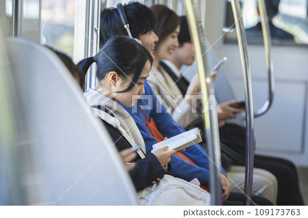 Female student reading on the train. Photography provided by Keio Electric Railway Co., Ltd. 109173763