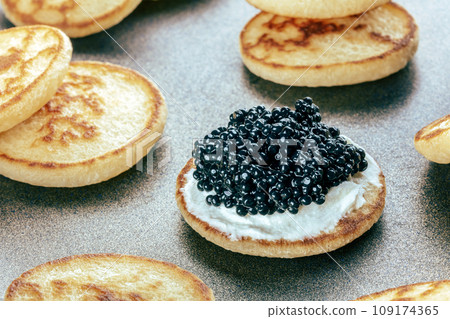 Blinis with black caviar and cream cheese, on a festive dish, mini pancakes 109174365