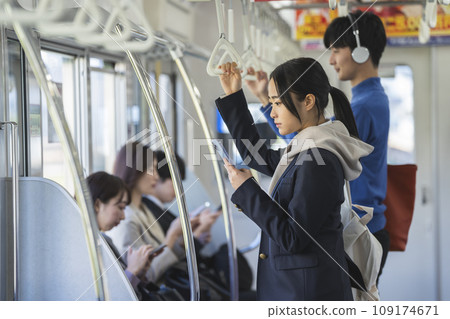 A female student looking at a smartphone screen on a train. Photographed with cooperation from Keio Electric Railway Co., Ltd. A female student looking at a smartphone screen on a train. Photographed with cooperation from Keio Electric Railway Co., Ltd. 109174671