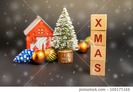 Wooden blocks with the word Xmas, miniature house and a Christmas tree. New Year or Xmas winter holiday. Decoration, celebration. The concept of the beginning of the new year. Snow, snowfall 109175168