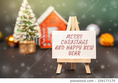 Easel with the words Happy New Year and Merry Christmas. New Year or Xmas winter holiday. Decoration, celebration. The concept of the beginning of the new year. Snow, snowfall 109175170